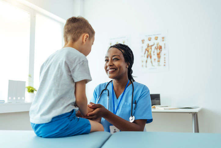 nurse talking with young boy in exam room