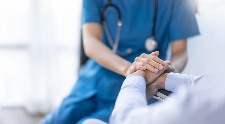 nurse holding a patients hand in bed