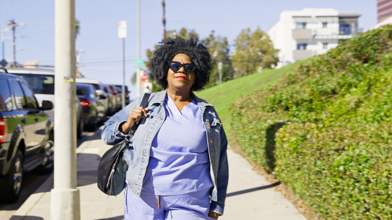 nurse in sunglasses walking down sidewalk